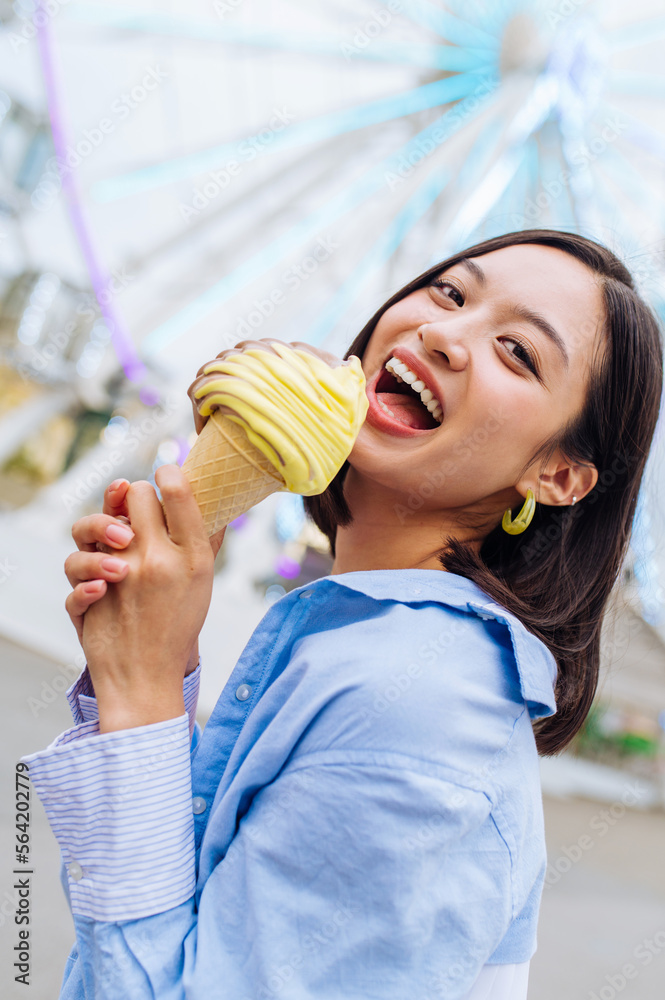 Beautiful young asian woman eating ice cream at amusement park - Cheerful chinese female portrait during summertime vacation- Leisure, people and lifestyle concepts