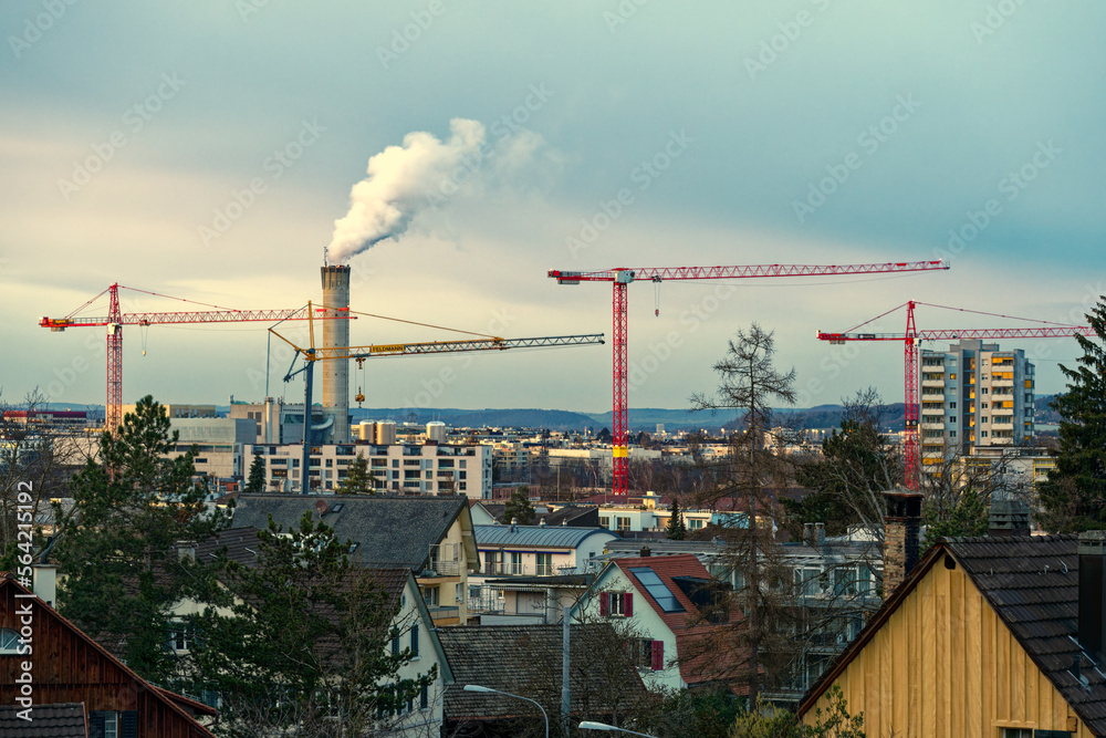 Skyline at City of Zürich district Schwamendingen with cranes and residential houses and beautiful colorful evening winter sky in the background. Photo taken January 10th, 2023, Zurich, Switzerland.