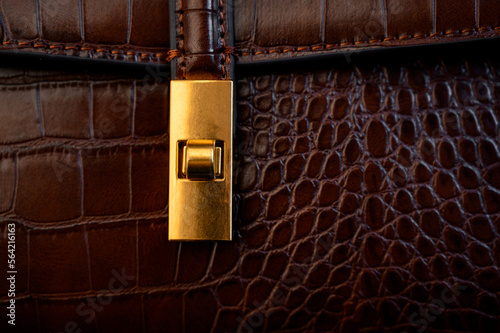 Lock on a leather bag. Close-up of bag closures. Brown crocodile effect bag