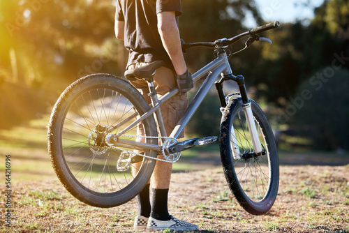 Bicycle, fitness and summer with a sports man outdoor in nature for leisure or recreation in summer. Back, bike and exercise with a male athlete standing on an open green field carrying his transport