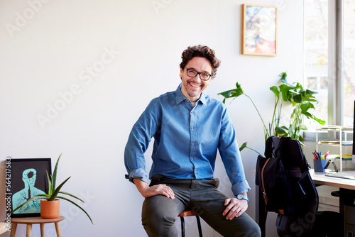 Cheerful man sitting on stool in office
