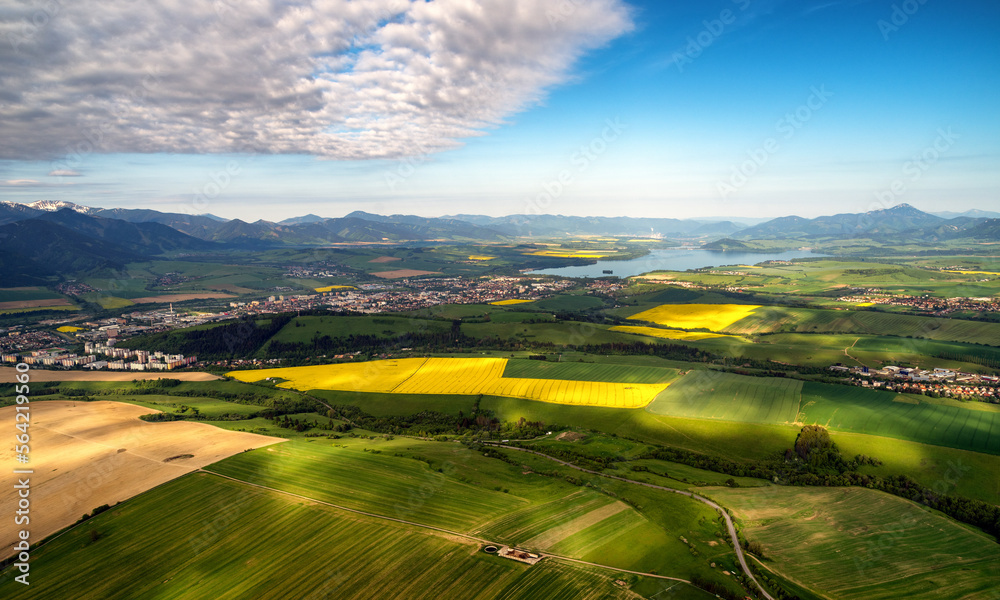 Beautiful country landscape with green, yellow fields and lake at background. Liptov, Slovakia