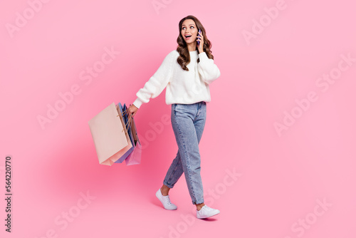 Full length photo of cute excited woman dressed white pullover talking device shopping empty space isolated pink color background
