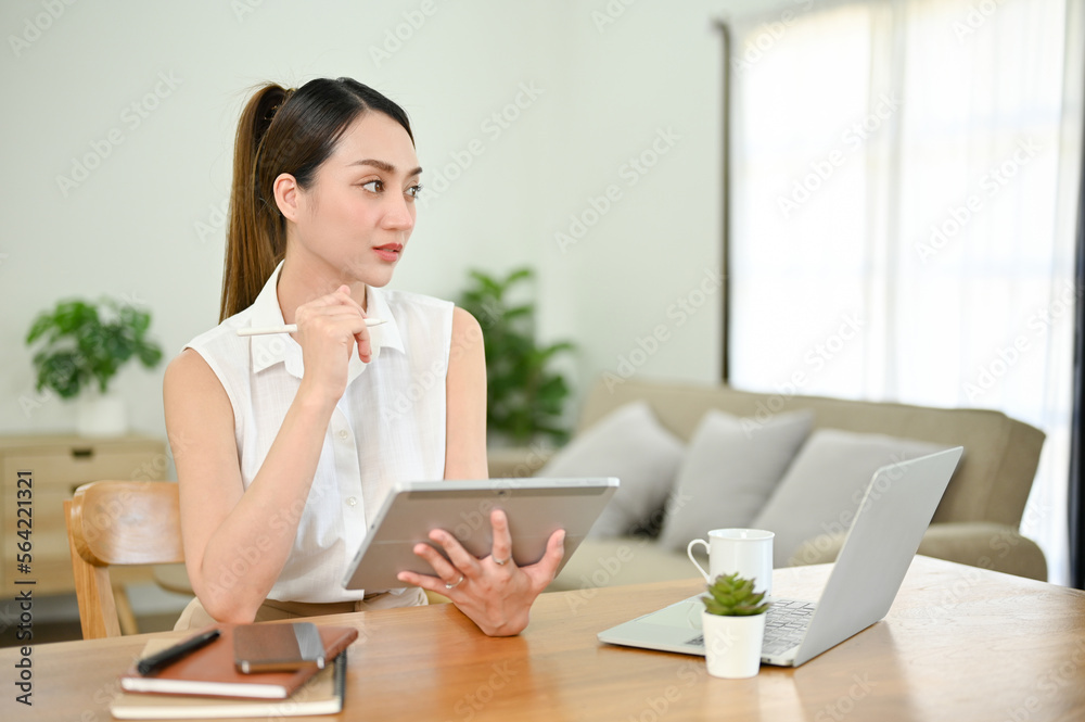 Thoughtful Asian businesswoman working from home, using tablet Thoughtful Asian businesswoman working from home, using tablet