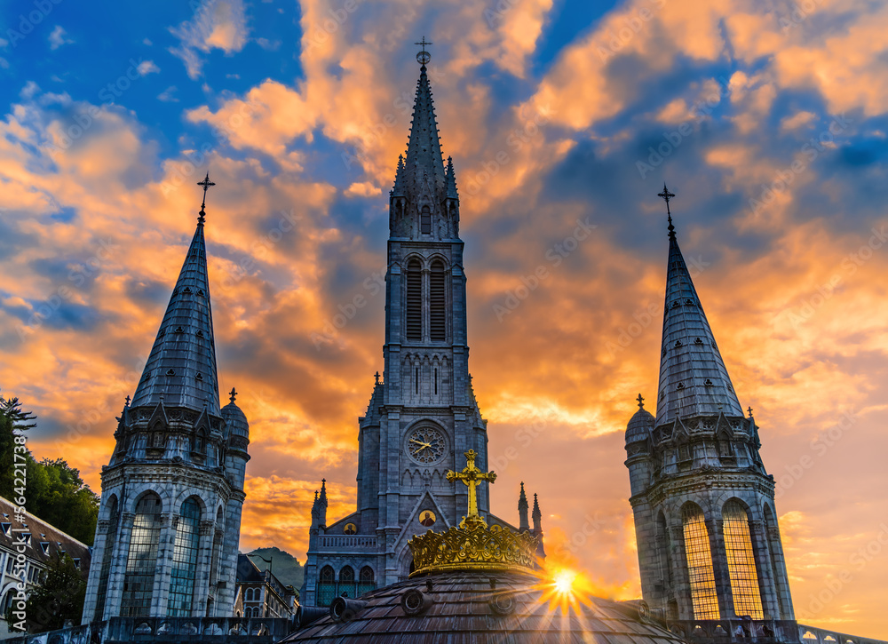 The sun star among the bell towers of the pilgrimage basilica of the apparitions of Mary in Lourdes The sun star among the bell towers of the pilgrimage basilica of the apparitions of Mary in Lourdes