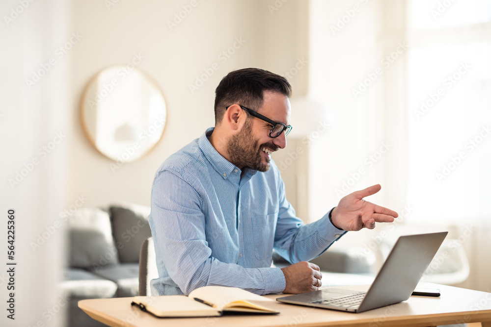 Happy businessman having an online meeting with colleagues, over the laptop, indoors. Happy businessman having an online meeting with colleagues, over the laptop, indoors.