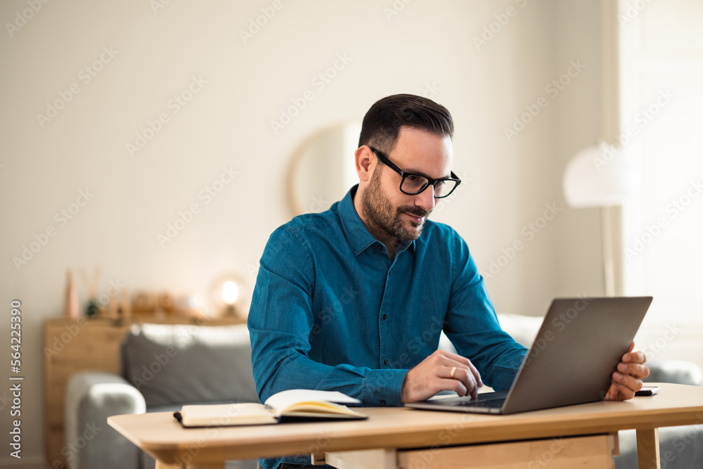 Focused man working over the laptop, sitting at the home office, with glasses on. Focused man working over the laptop, sitting at the home office, with glasses on.