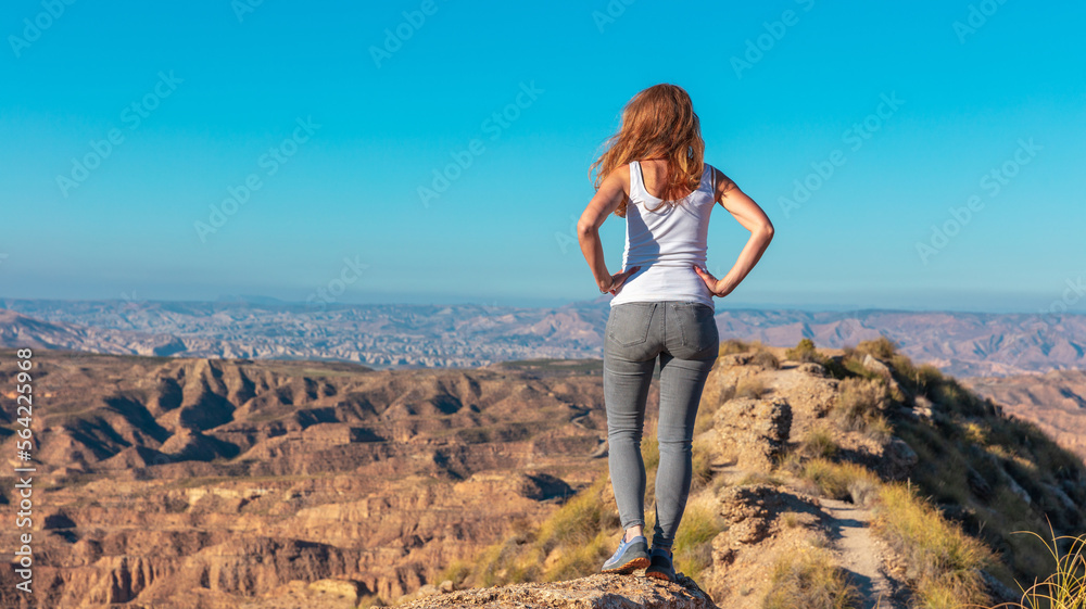 Woman standing on rock and looking at panoramic Gorafe mountain desert landscape view Woman standing on rock and looking at panoramic Gorafe mountain desert landscape view
