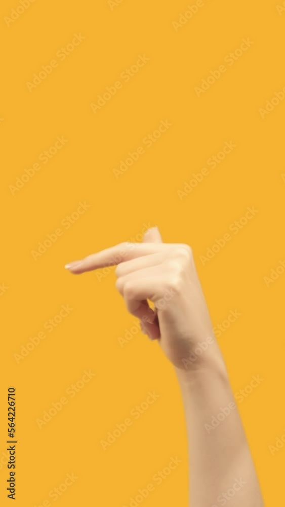 Vertical video. Finger pointing. Previous page. Recommending gesture. Female hand sign recommending something before on orange empty space background. Vertical video. Finger pointing. Previous page. Recommending gesture. Female hand sign recommending something before on orange empty space background.