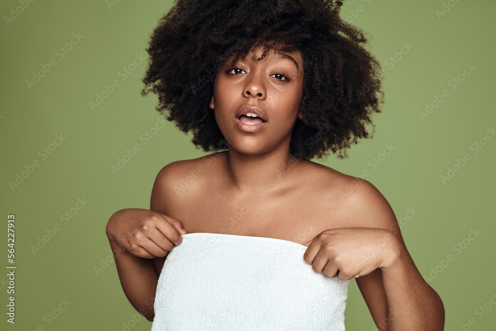 Young ethnic lady with towel around body looking at camera in studio Young ethnic lady with towel around body looking at camera in studio