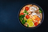 Tom Yum - Thai soup with prawns, shiitake mushrooms and noodles on wooden table
