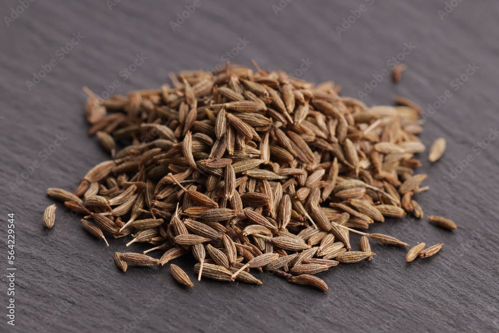 a bunch of natural dried cumin on a gray stone plate. side view