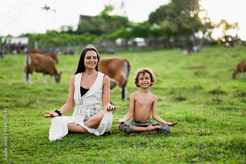 Happy mom and son doing yoga in nature and smiling