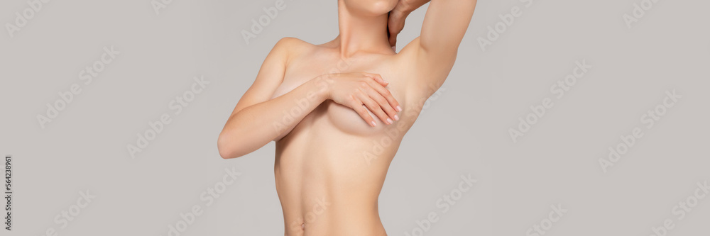 Cropped image of slim female body over grey studio background. Woman covering breast with hand. Female health care. Concept of body and skin care, health, wellness. Banner, flyer. Copy space for ad Cropped image of slim female body over grey studio background. Woman covering breast with hand. Female health care. Concept of body and skin care, health, wellness. Banner, flyer. Copy space for ad