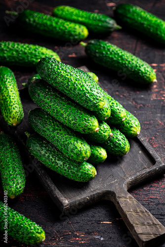 Fresh cucumbers on a wooden cutting board. 