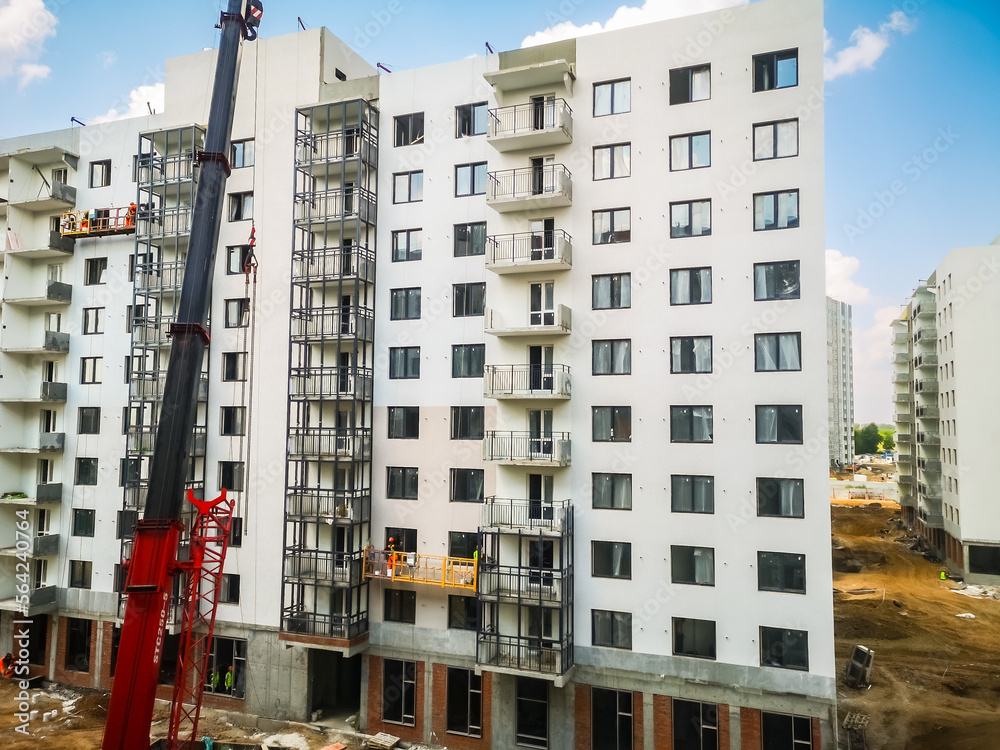 Fototapeta premium a crane lifts building materials for builders of new houses from monolithic reinforced concrete. Construction of apartments in a new residential complex