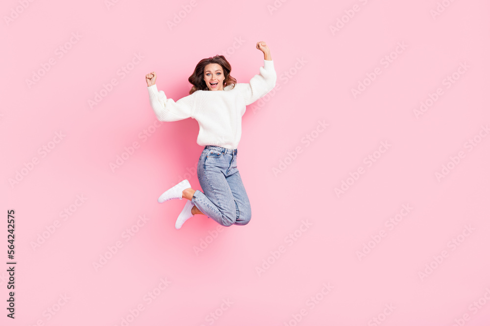 Full length photo of shiny lucky woman dressed white pullover jumping high rising fists empty space isolated pink color background