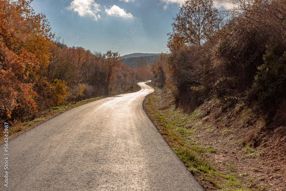 Asphalt road with curves in Autumn and sky with clouds