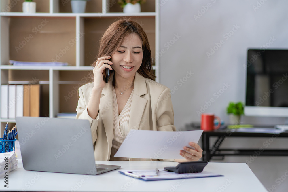 Asian businesswoman working with financial documents, discussing with clients with smartphone and laptop computer on table, analysis plan, financial report. Business plan. Investment finance concept. Asian businesswoman working with financial documents, discussing with clients with smartphone and laptop computer on table, analysis plan, financial report. Business plan. Investment finance concept.
