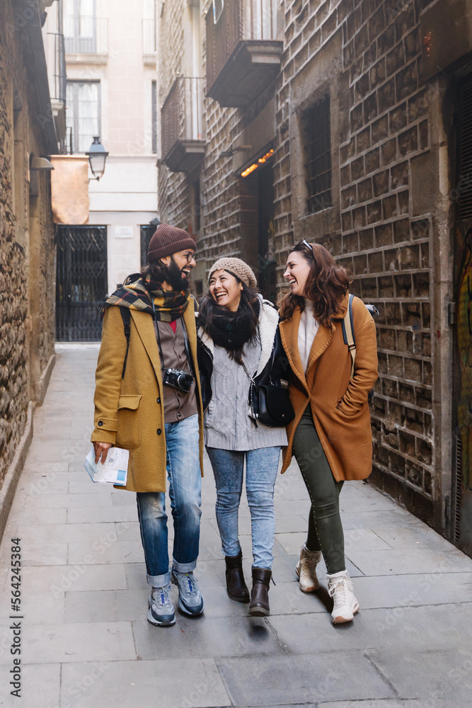 Three tourist friends walking in European city old town, happy sightseeing and enjoying winter vacations 
