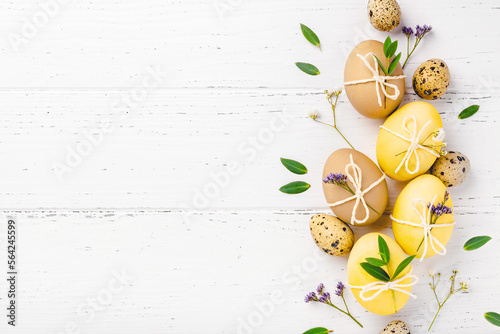 Festive Easter background. Easter eggs with flowers on a white table. Flat lay  place for text.