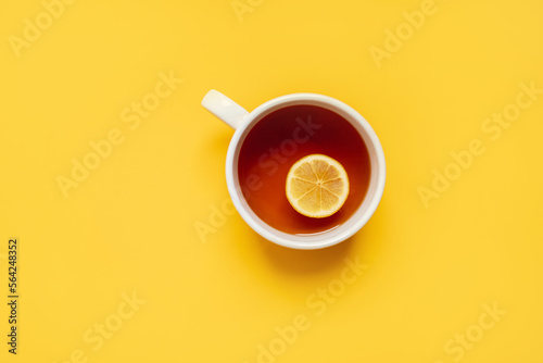 
black lemon tea in a large cup on a yellow background with a yellow blanket and lemons. copy space. top view. flat lay. photo