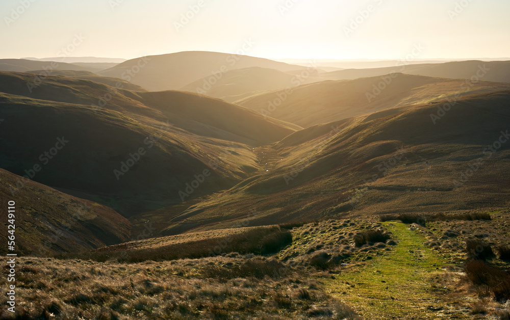 The twisting valley of Rowhope Burn from the summit of Black Braes on a sunny winters morning in the Northumberland Cheviot mountains at sunrise, UK.