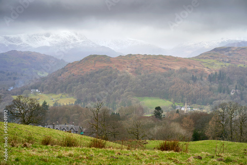 Loughrigg Fell with distant views of the snow covered summit of Wetherlam and Wynrose Pass from below Wansfell Pike in the Cumbrian Lake District Mountains, England UK. photo