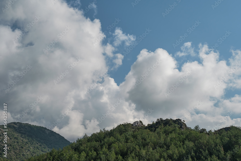Beautiful view of the mountains with pine trees and white fluffy clouds, panoramic shot of the mountains at noon on the Aegean coast