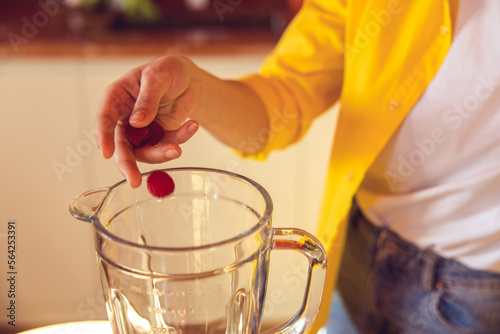 Close up of a female hand putting raspberry to the glass