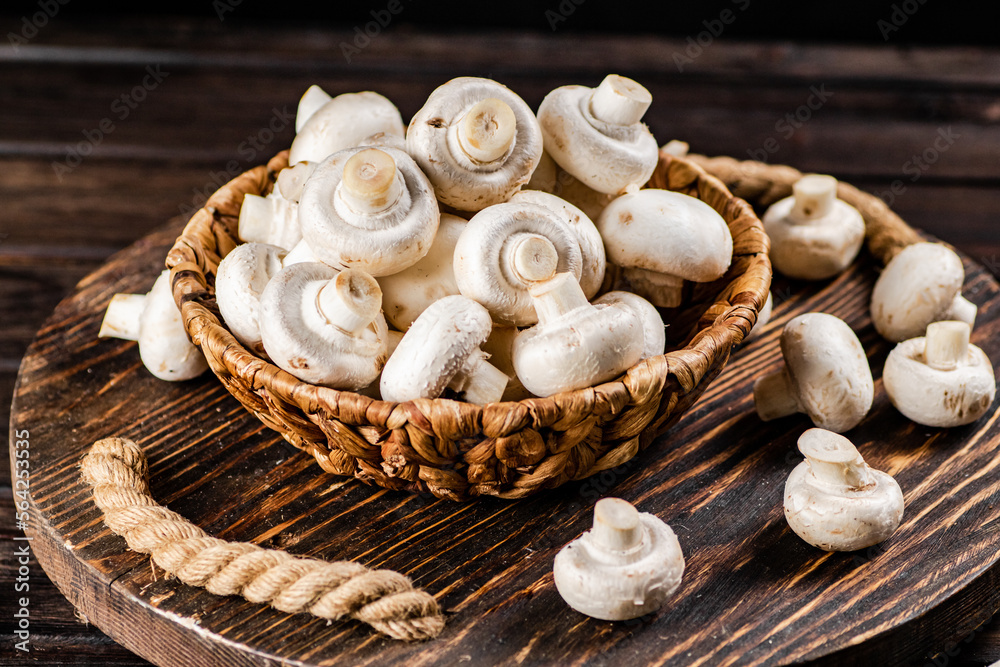 Fresh mushrooms in a basket on a wooden tray. 