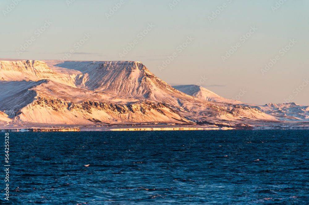 imagen de un paisaje de montañas nevadas con el cielo azul y el mar en la parte inferior