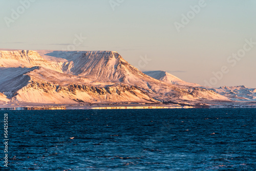 imagen de un paisaje de montañas nevadas con el cielo azul y el mar en la parte inferior