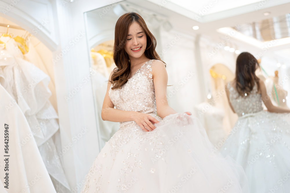 Asia young is smiling while choosing wedding dress in modern wedding salon