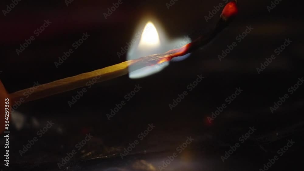 Match lighting up and burning flame against black background.