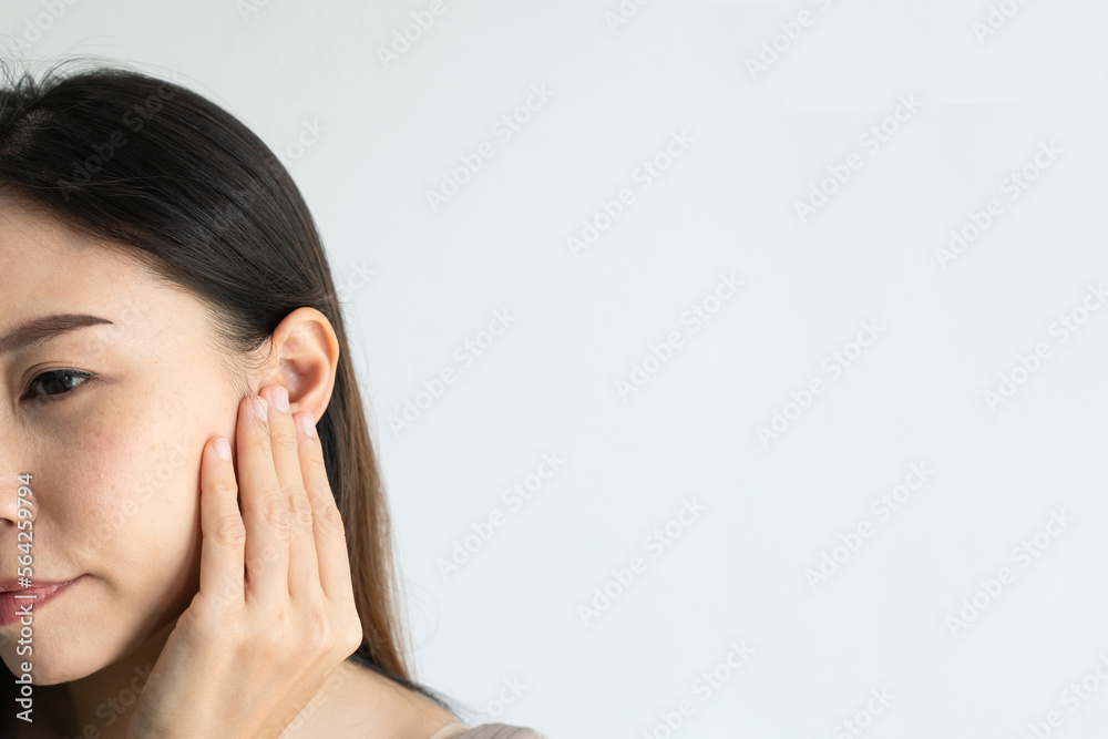 Young Asian woman with sore ear suffering from otitis over white background. Girl touch her ear with pain. Ear problem, health concept. Copy space, closeup Young Asian woman with sore ear suffering from otitis over white background. Girl touch her ear with pain. Ear problem, health concept. Copy space, closeup