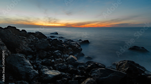 Wide angle long exposure shot of sunset at sea. Coastal rocks in the foreground. Black sea shore.