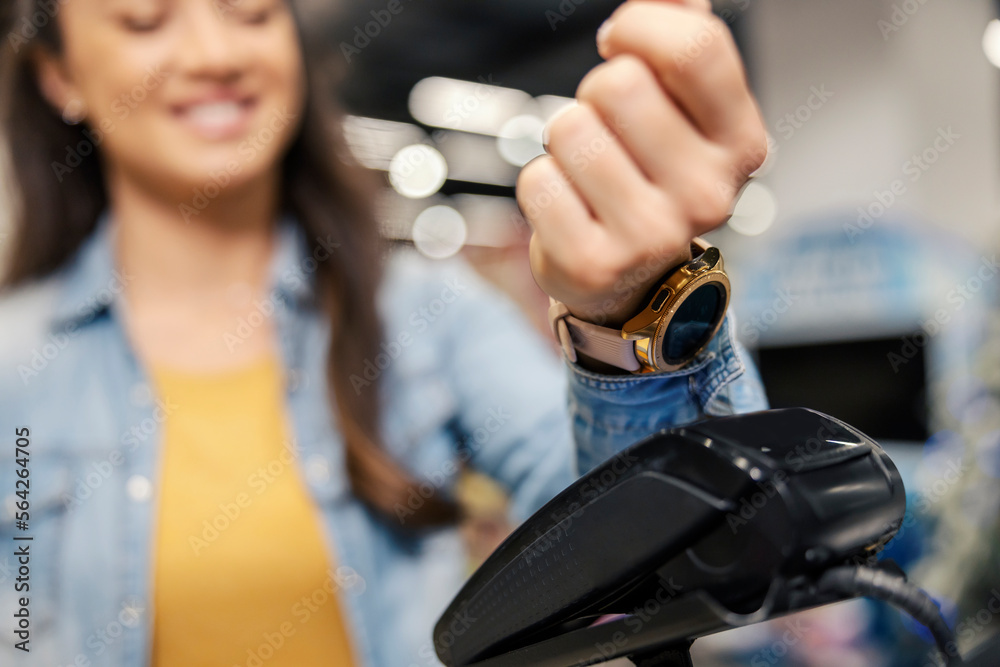 Close up of a woman paying with smart watch app on pos terminal in supermarket.