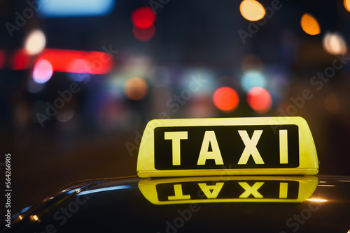 Selective focus on taxi sign on roof of car against busy city street at night. .