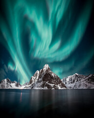 Papier peint photo Photos Northern lights, Aurora borealis over amazing landscape in Lofoten, Norway  with mountains in background, Absolutely stunning and beautiful lights on the sky  © Dominik
