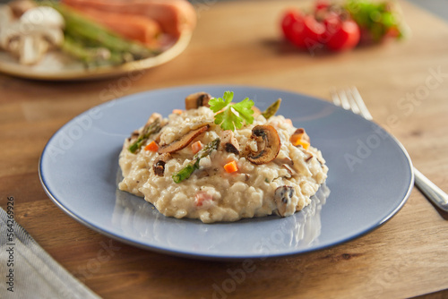Risotto with mushrooms and asparagus on an old wooden table in blue plate