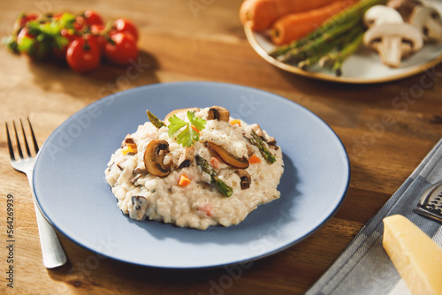 Risotto with mushrooms and asparagus on an old wooden table in blue plate