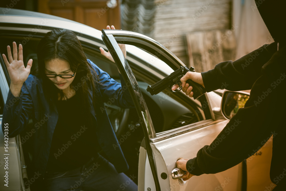 Robber threatened driver car on street. Thief use gun to intimidate asian woman for give car key