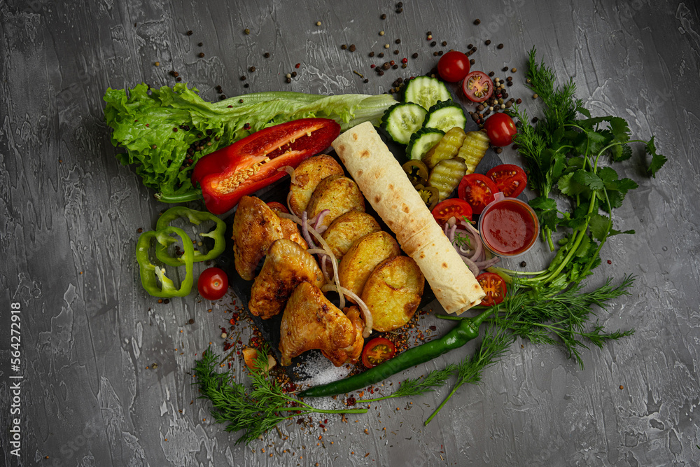 grilled chicken wings with fried potatoes, cucumbers, cherry tomatoes and ketchup on a gray background, pita bread, greens, dill grilled chicken wings with fried potatoes, cucumbers, cherry tomatoes and ketchup on a gray background, pita bread, greens, dill