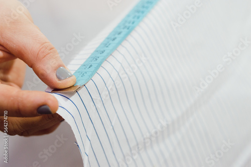 close-up of female hand extending a tape measure along the edge of a cloth  copy space 