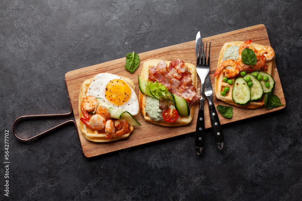 Breakfast waffles with fried eggs, salmon, cucumber and prawns