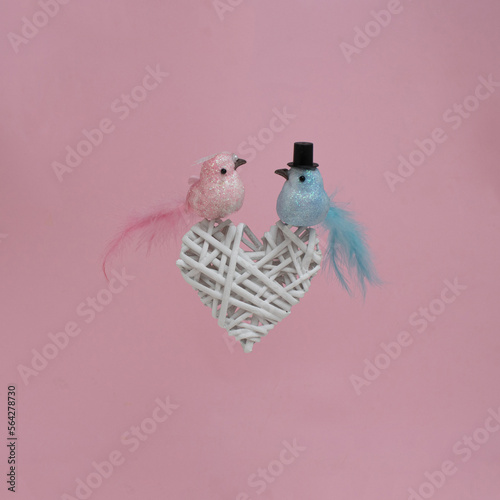 Two love birds on white heart. Valentine's concept on pink background.