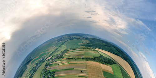 Aerial view from high altitude of little planet earth with green and yellow cultivated agricultural fields with growing crops on bright summer day