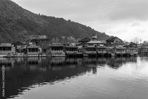 Kashmir, Srinagar India - Jan 10 2023: Popular Srinagar Houseboats in Dal Lake. Colorful Shikara ride floating in Dal Lake aka Nigeen lake. Mountain range in Srinagar. Couple Honeymoon Destination. 