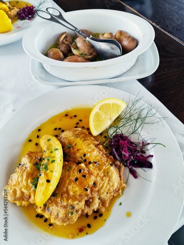 Filete de Espada with banana and passion fruit sauce. The black swordfish - the most typical fish on the island of Madeira. Typical madeiran dish Espada on white plate with potatoes as a side dish.  photo